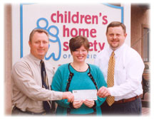 At left, WFEC Manager of Member Services and Communication Terry Mullen and, at right, Gulf Coast Electric Cooperative Manager of Marketing and Member Services Michael White present a $2,500 check to Children’s Home Society of Florida Development Director Wendy F. Davis.